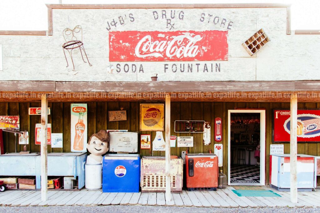 Products made by coca-cola and coke companies displayed in-front of an old convenience store